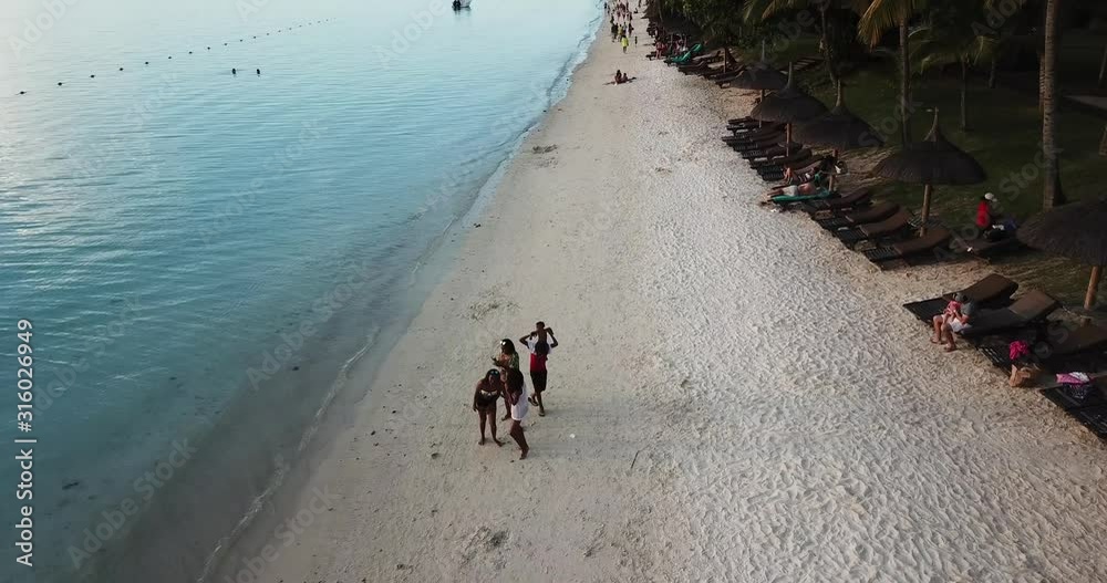 Mauritius, Trou aux Biches - May 12. 2019; Flight above beach at the sunset showing people enjoying.
