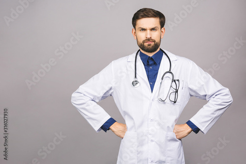 Angry serious male doctor looking at you with stethoscope around his neck  serious face isolated on grey background.