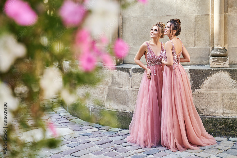Beautiful bridesmaids in gorgeous elegant stylish red pink violet floor length v neck chiffon gown dress decorated with sequins sparkles and rhinestones holding flowers bouquets. Wedding day in old