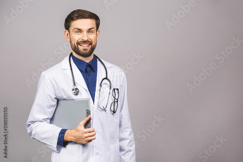 Portrait of smiling male doctor holding clipboard isolated on grey background.