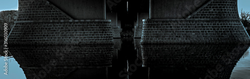 The neighborhood of the bridge is reflected in the river at sunrise