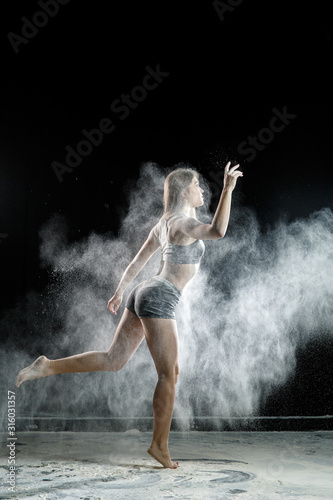 Beautiful girl model on a black background throws flour © Анастасия Комарова