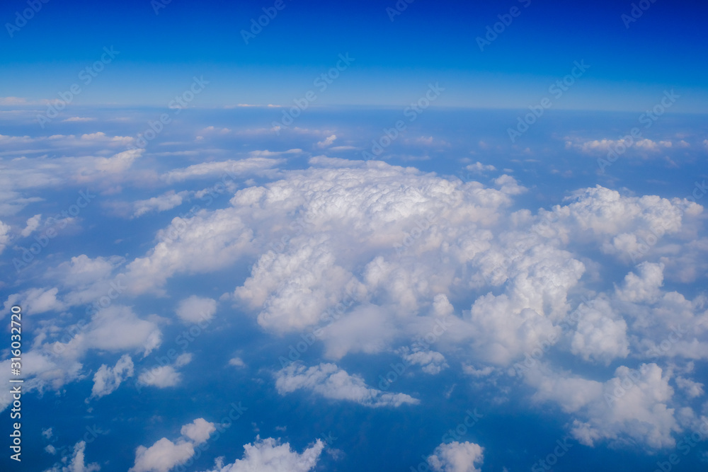 Fluffy white cloud with blue sky above view from airplane