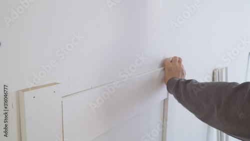 arpenter using nail gun nstallation mouldings on the wall of fragment of molding, photo