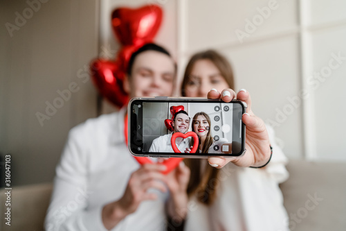 selfie on the phone screen of handsome couple at home on couch with heart