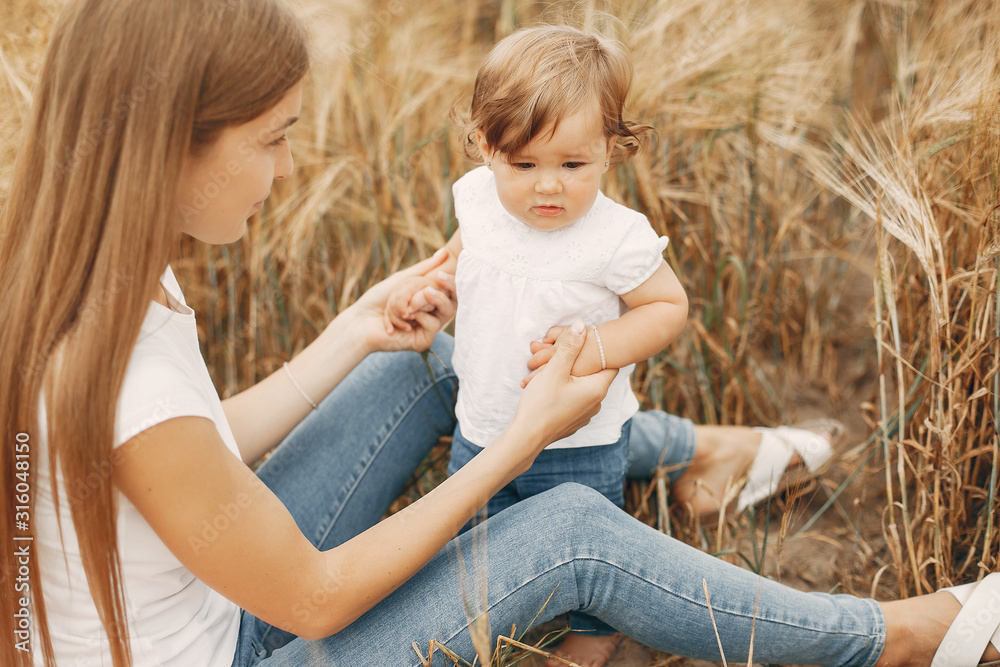Family in a summer field. Mother in a white t-shirt. Cute little girl Family in a summer field. Mother in a white t-shirt. Cute little girl