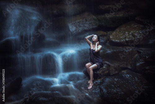 Naked woman washing in waterfall