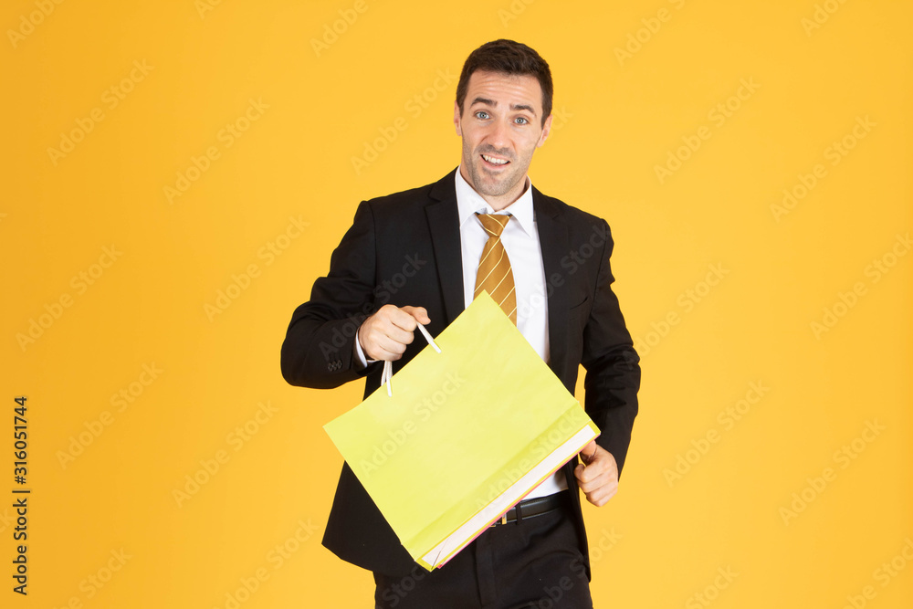 Portrait of businessman with shopping bags on yellow background. Portrait of businessman with shopping bags on yellow background.