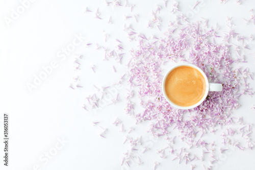 Morning breakfast with coffee cup and lilac flowers on white background. Flat lay, top view women background. Minimal concept, wedding, valentine day, copy space