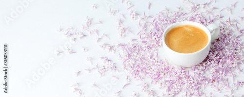 Morning breakfast with coffee cup and lilac flowers on white background. Flat lay, top view women background. Minimal concept, wedding, valentine day, copy space, banner