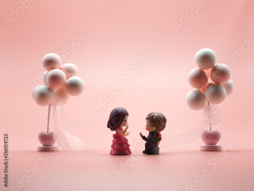 Couple toy dool boyfrend Kneel to propose just married surprise romantic girlfriend.Male Hand over the ring female between Two balloon and pink white isolate background 14 fourteen feb Valentine   photo