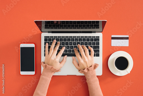 stylish young girl working analytics typing on laptop and papers flat lay