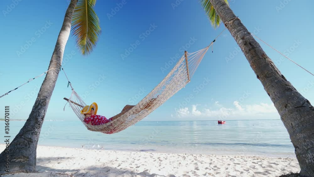 Girl relaxing in a hammock on tropical island beach. Summer vacation in Punta Cana, Dominican Republic