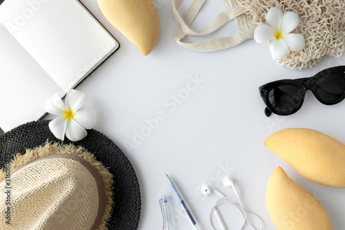 Flat lay top view traveler accessories, fruits, straw hat on white background with empty space for text
