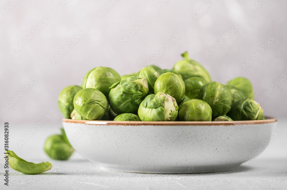 Organic raw and fresh brussel sprouts on a plate on light background