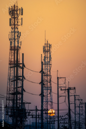 Silhouette of high voltage electrical pole on sunset sky background.