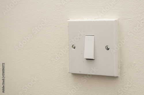 A simple white electrical light switch on a white wall. Industrial, residential or DIY construction concepts.