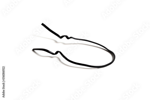 Black used piece of wire for pulling electric cables and other things on a white background isolate. Black plastic coated wire tie. Cable flexible tie tools for packing. Top view.