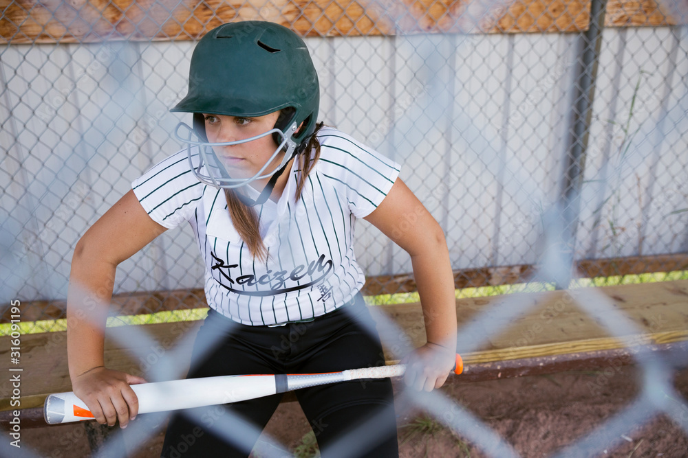 Serious middle school girl softball player wearing batting helmet and