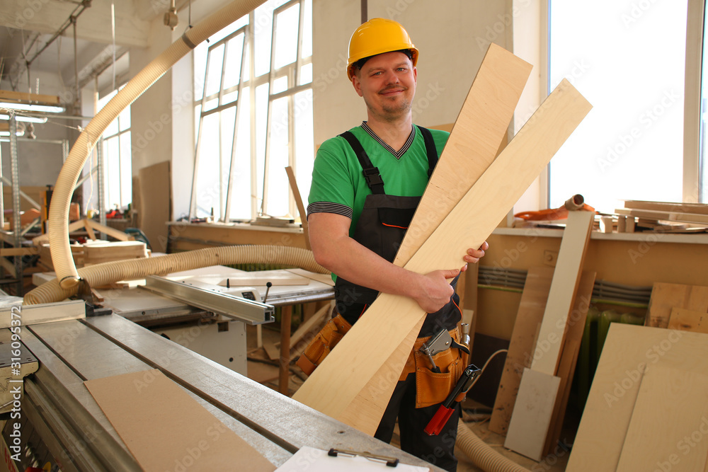 Portrait of a smiling carpenter holding wood planks in a construction site Portrait of a smiling carpenter holding wood planks in a construction site