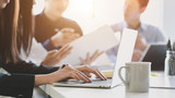 Close up view of business people typing on computer laptop while working with her team