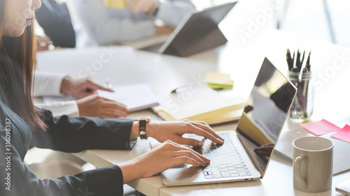 Cropped shot of business people typing on computer laptop while working with her team