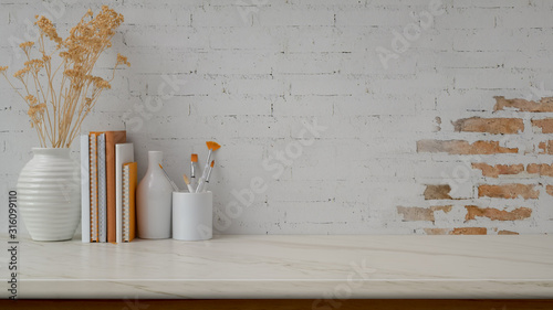 Cropped shot of workspace with copy space, vases, paint brush and books on marble desk with brick wall