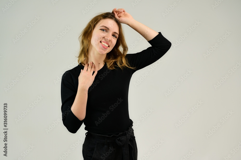 Portrait of a pretty blonde girl in a black t-shirt on a white background with emotions. A universal concept, the picture is suitable for any topic. Portrait of a pretty blonde girl in a black t-shirt on a white background with emotions. A universal concept, the picture is suitable for any topic.