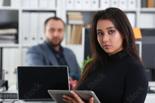 young pretty brunette woman in office work with her boss hold tablet in hands