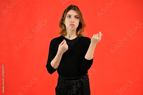 A universal concept, the picture is suitable for any topic. Studio portrait of a pretty blonde girl in a black T-shirt on a red background with bright emotions.