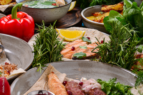 Traditional Georgian cuisine. Salmon steak with nut sauce with pomegranate seeds and lemon surrounded by other dishes. photo