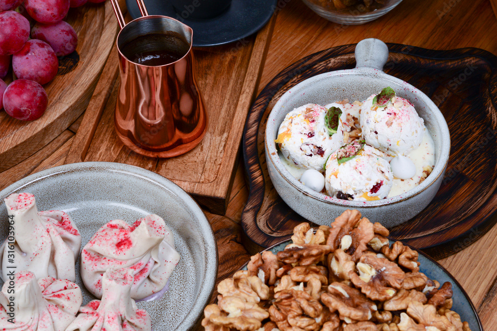 Sweet khinkali, churchhela, ice cream and nuts served on a table. Turkish coffee in traditional embossed cup cezve.