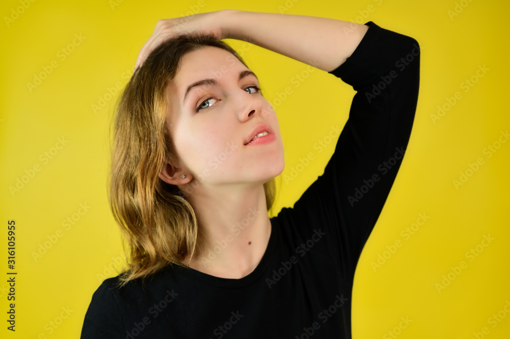 Close-up Studio portrait of a pretty blonde girl in a black T-shirt on a yellow background with bright emotions. A universal concept, the picture is suitable for any topic. Close-up Studio portrait of a pretty blonde girl in a black T-shirt on a yellow background with bright emotions. A universal concept, the picture is suitable for any topic.
