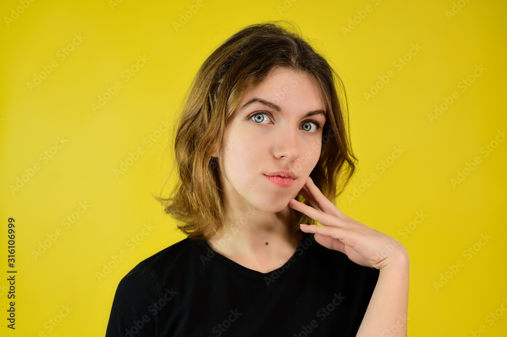 A universal concept, the picture is suitable for any topic. Close-up Studio portrait of a pretty blonde girl in a black T-shirt on a yellow background with bright emotions. A universal concept, the picture is suitable for any topic. Close-up Studio portrait of a pretty blonde girl in a black T-shirt on a yellow background with bright emotions.