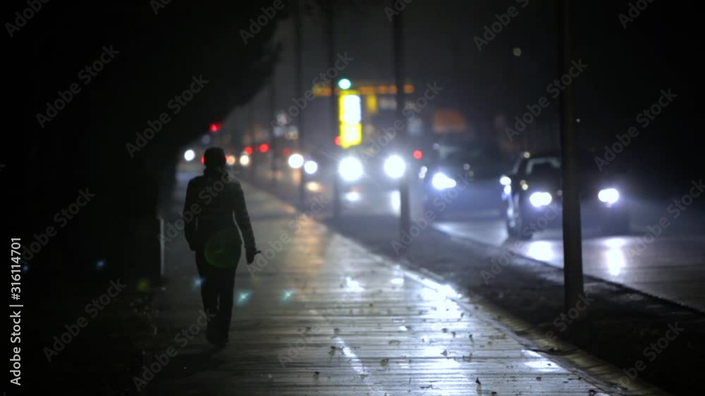 View of a woman walking on the path. Traffic in the city at night View of a woman walking on the path. Traffic in the city at night