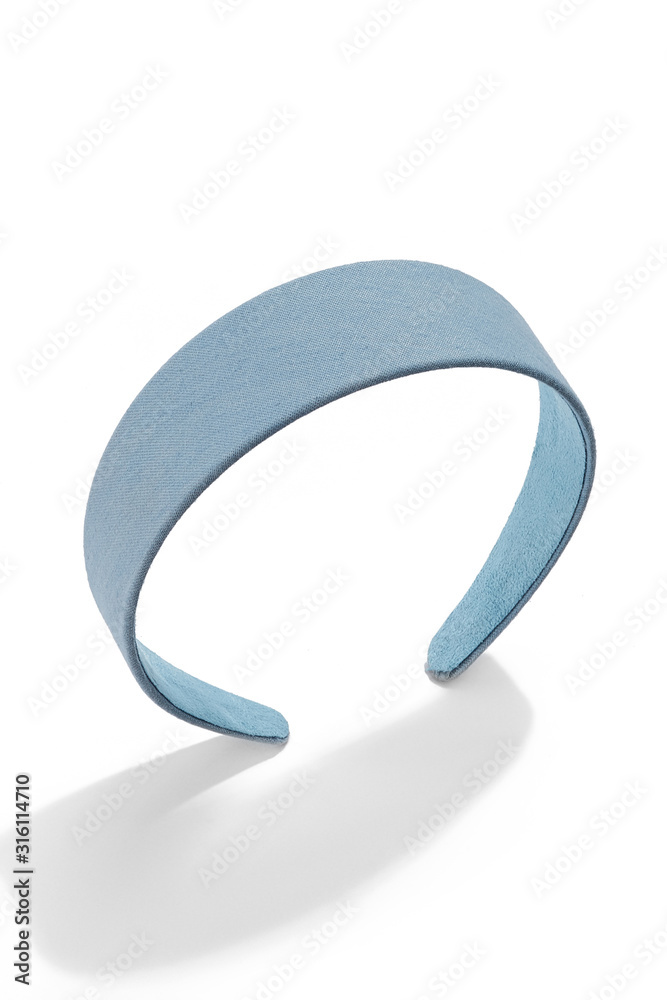 Subject shot of a wide hairband covered with a light blue denim fabric. The stylish headband is isolated on the white background with shadows. Subject shot of a wide hairband covered with a light blue denim fabric. The stylish headband is isolated on the white background with shadows.