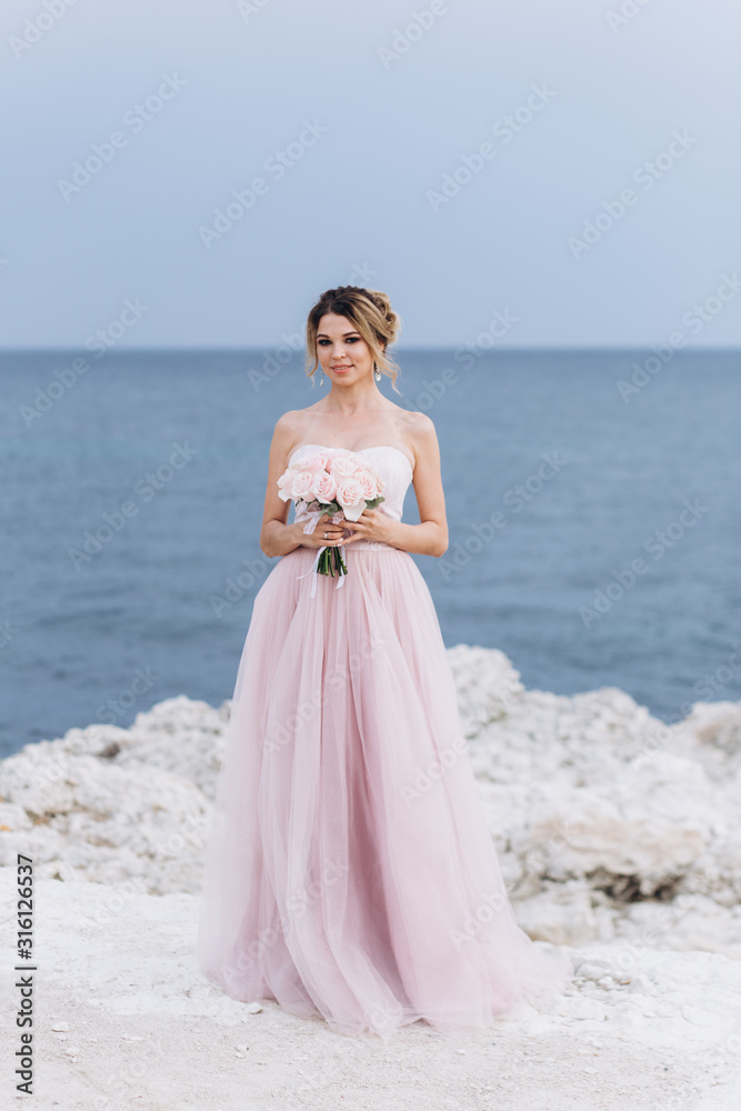 Portrait of a young beautiful bride with a bouquet of roses near the sea. Portrait of a young beautiful bride with a bouquet of roses near the sea.