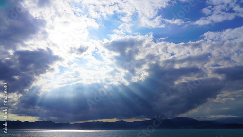 dramatic sky  dark clouds on a blue sky  the rays of the sun pass through the clouds in lines. glow of heaven at sea. ocean