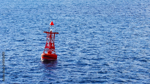 Red coastal buoy in blue ocean water. safety and navigation of ships near the shore photo