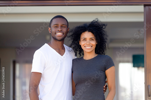 Portrait of happy black couple posing outside own home