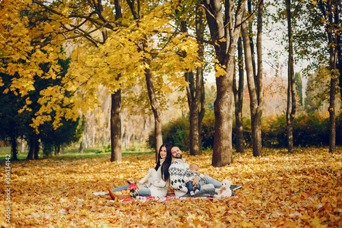 Family in a autumn park. Woman in a white sweater. Cute newborn little boy with parents