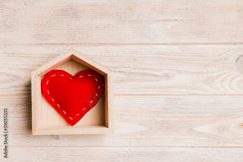Top view of red textile heart in a house on wooden background. Home sweet home concept. Valentine's day