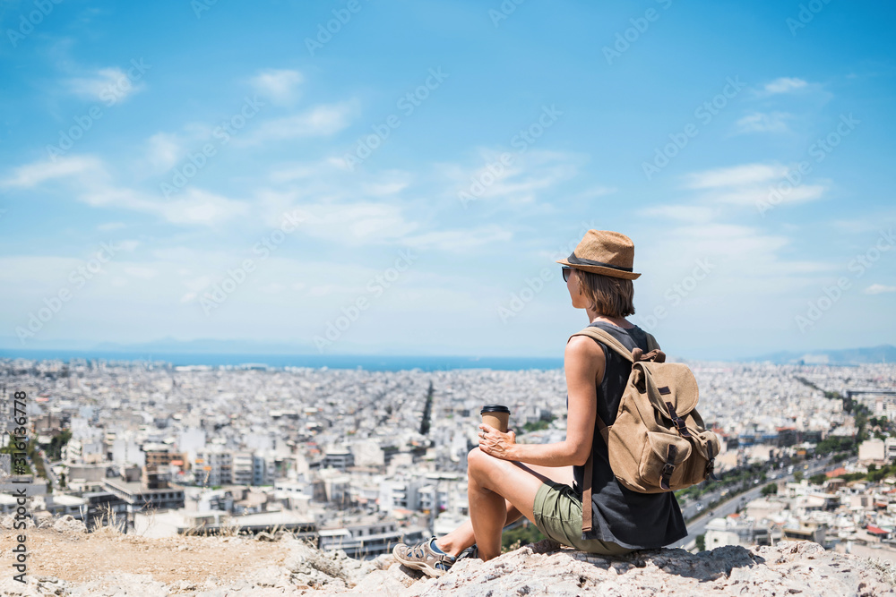 Traveler girl enjoying vacations. Young woman wearing hat looking at big city. Summer holidays, vacations, travel, tourism concept.	