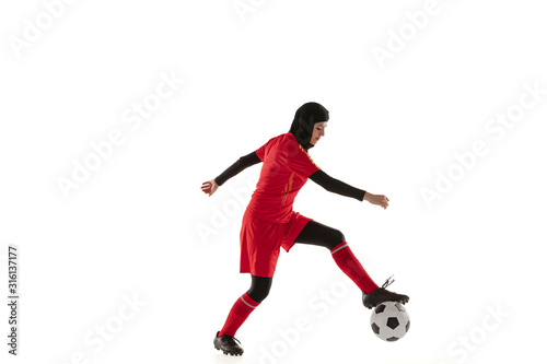 Fototapeta Naklejka Na Ścianę i Meble -  Arabian female soccer or football player isolated on white studio background. Young woman kicking the ball, training, practicing in motion and action. Concept of sport, hobby, healthy lifestyle.