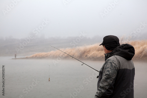 male fisherman fishing in a winter pond