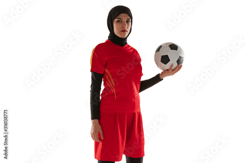 Arabian female soccer or football player isolated on white studio background. Young woman holding the ball, training, practicing in motion and action. Concept of sport, hobby, healthy lifestyle.