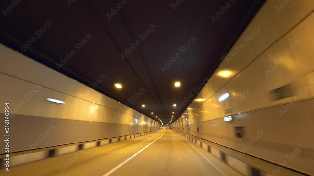 Car ride through underground tunnel road. Tube night illumination. Fast moving inside motorway mountain pass. Travel tourist bus Russia Sochi Europe. Car ride through underground tunnel road. Tube night illumination. Fast moving inside motorway mountain pass. Travel tourist bus Russia Sochi Europe.