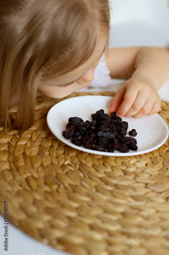 little girl eating raisins. natural vitamins