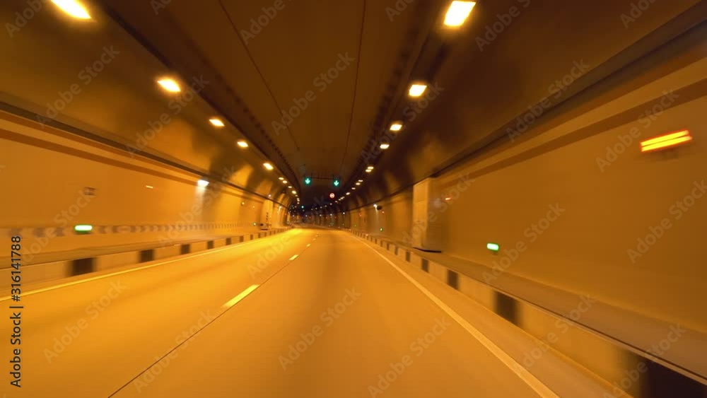 Longest tunnel first person driver view gimbal forward 4K. Car ride through underground tunnel road. Tube night orange illumination. Fast moving inside. Travel tourist bus Alpine Europe. Longest tunnel first person driver view gimbal forward 4K. Car ride through underground tunnel road. Tube night orange illumination. Fast moving inside. Travel tourist bus Alpine Europe.