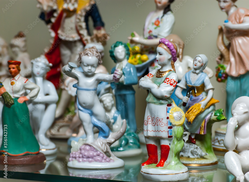 Assortment of rare porcelain figurines on glass shelf